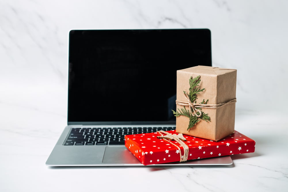 Tech gifts for Christmas for the tech-obsessed person. Gadgets and devices Xmas gift ideas. Laptop with Christmas Gift boxes on the table